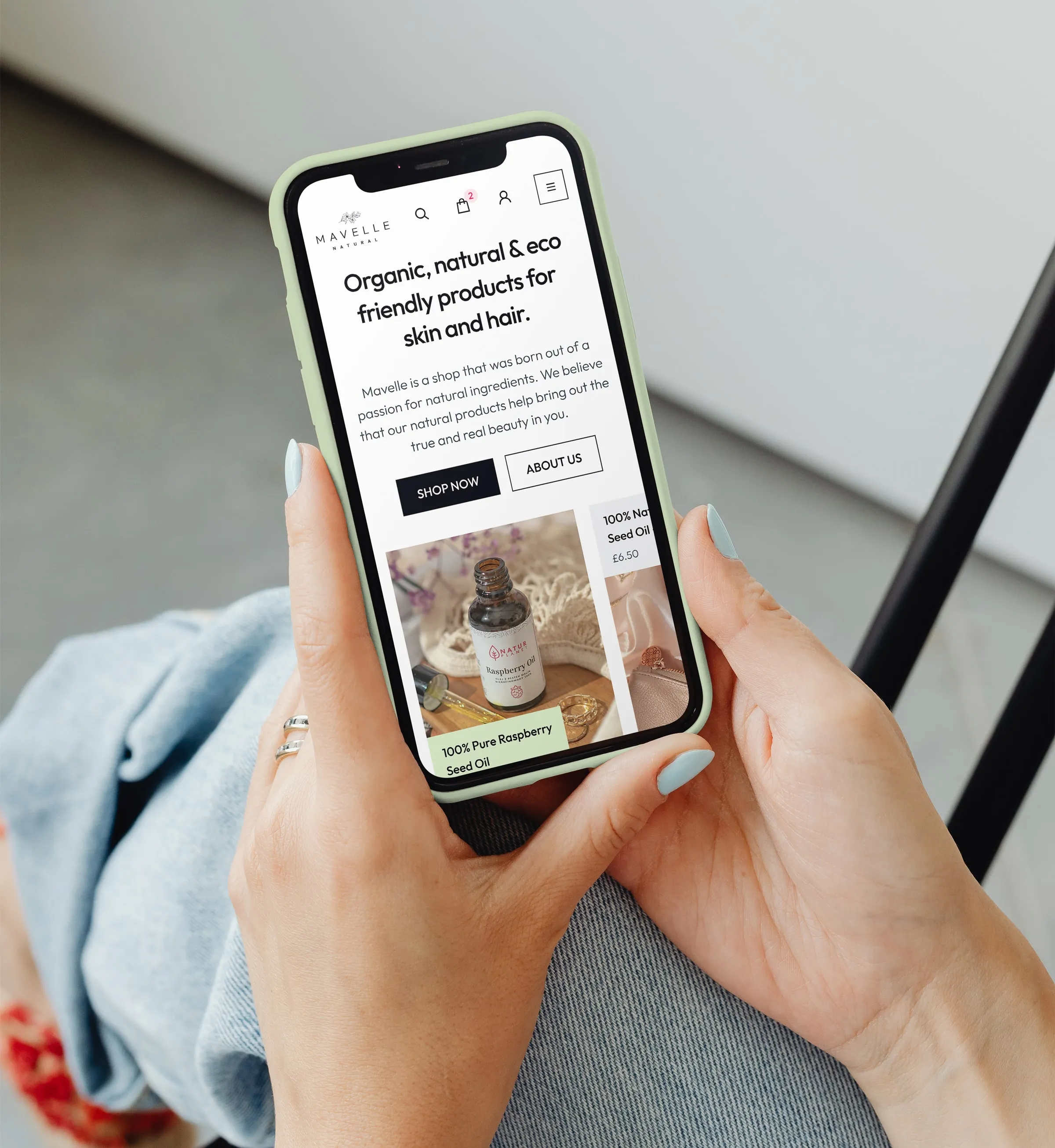 Hands holding a phone that shows the mobile Mavelle homepage